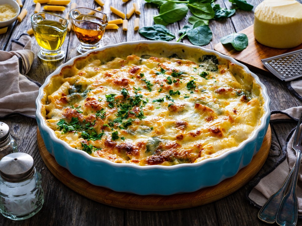 Eine runde Backform mit Nudelauflauf mit Feta und Spinat und mit Käse überbacken, mit Petersilie bestreut.