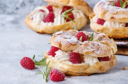 Drei kleine Paris-Brest, mit Himbeeren und Rosmarin garniert.