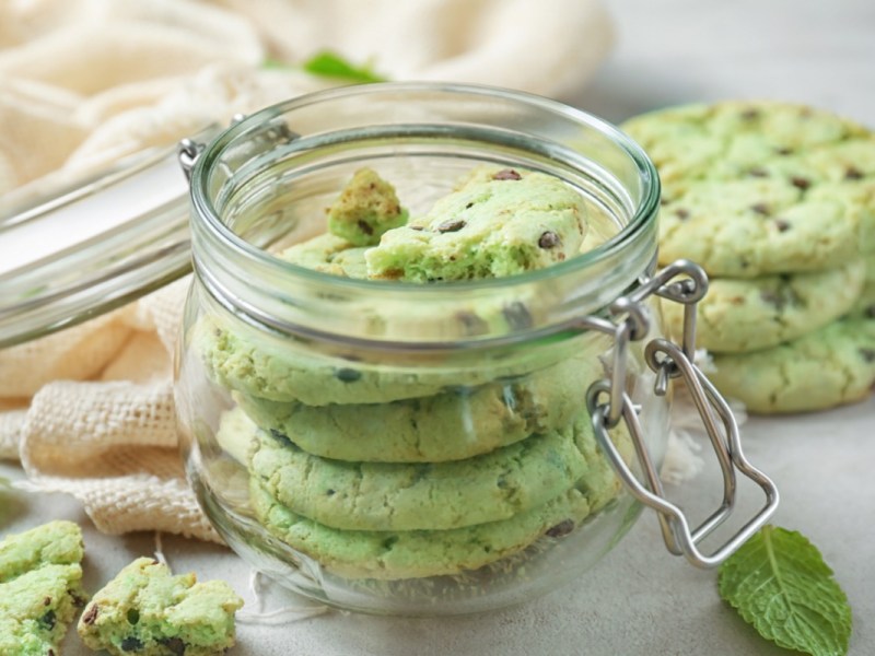 Schoko-Minz-Cookies in einem Einweckglas. Mehre Kekse liegen daneben.