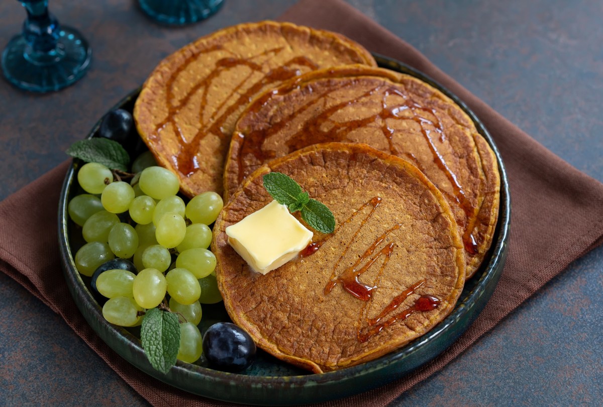 SÃ¼ÃŸkartoffel-Pancakes mit Butter und Weitrauben auf dunklem Teller