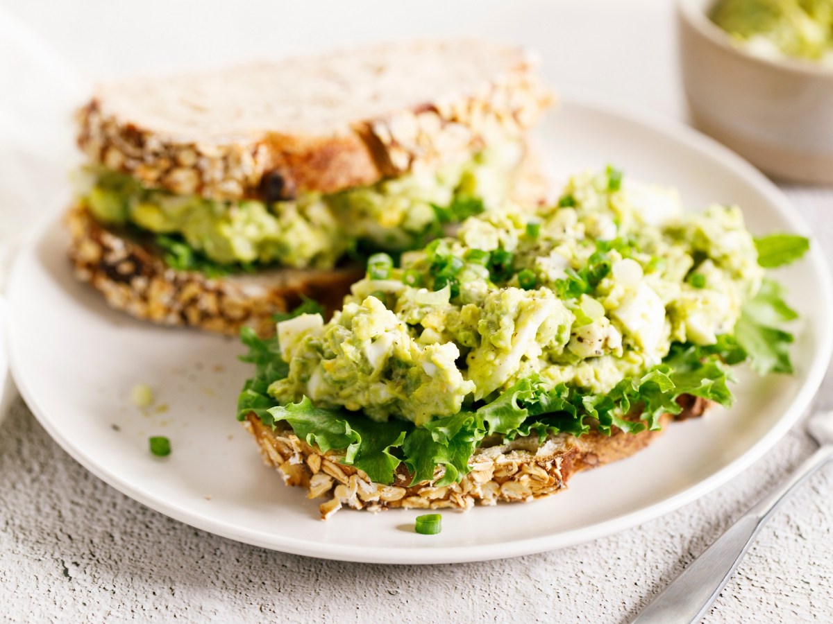 Avocado-Eiersalat auf zwei Broten, die auf einem Teller liegen.