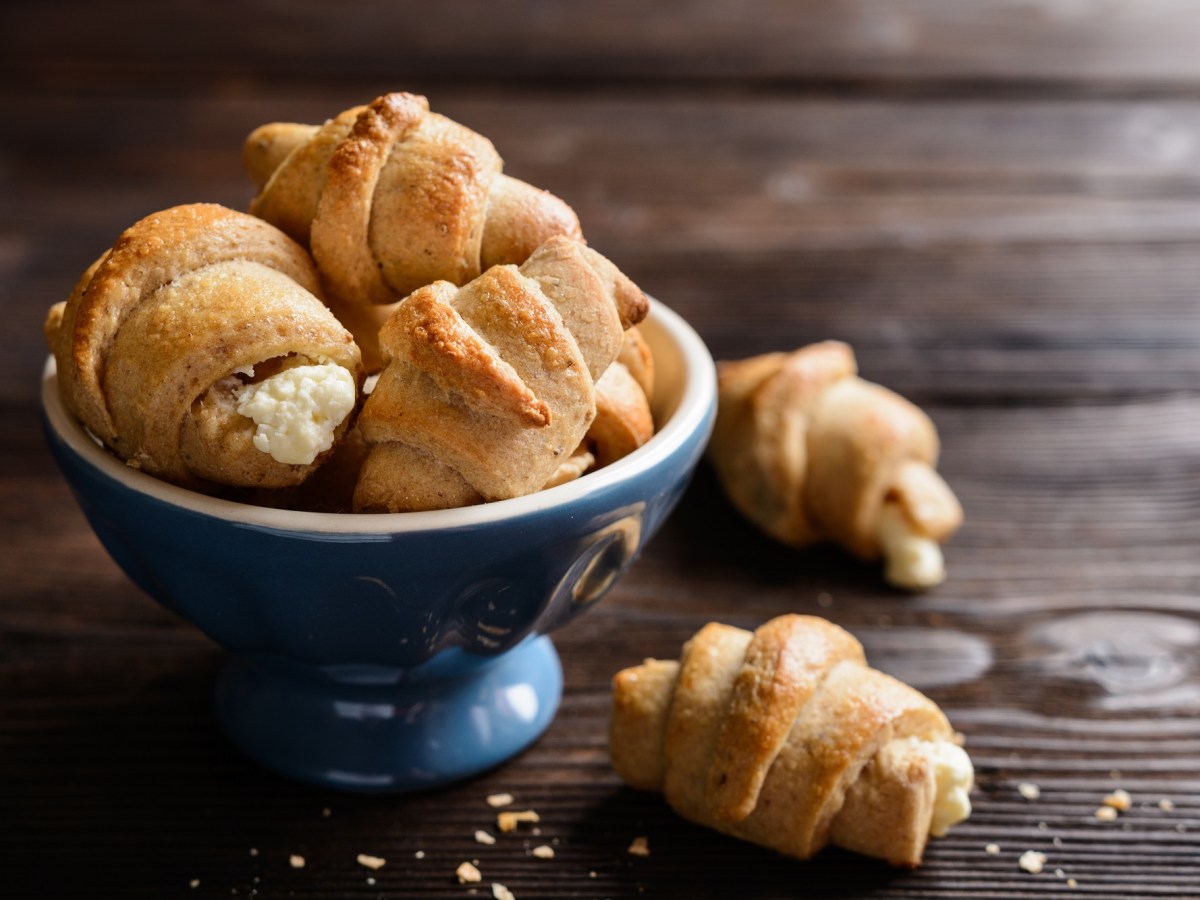 Kartoffel-Croissants mit Käsefüllung in einer Schüssel, zwei Stück liegen daneben.