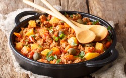 Picadillo, mexikanische Hackfleischpfanne, auf der zwei Holzlöffel liegen.