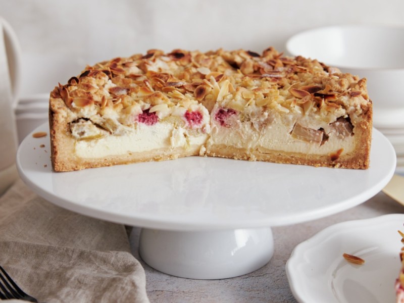 Ein halber Rhabarber-Käsekuchen auf einer Toretenplatte.