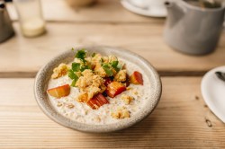 Schale mit Rhabarber-Porridge auf Holztisch.