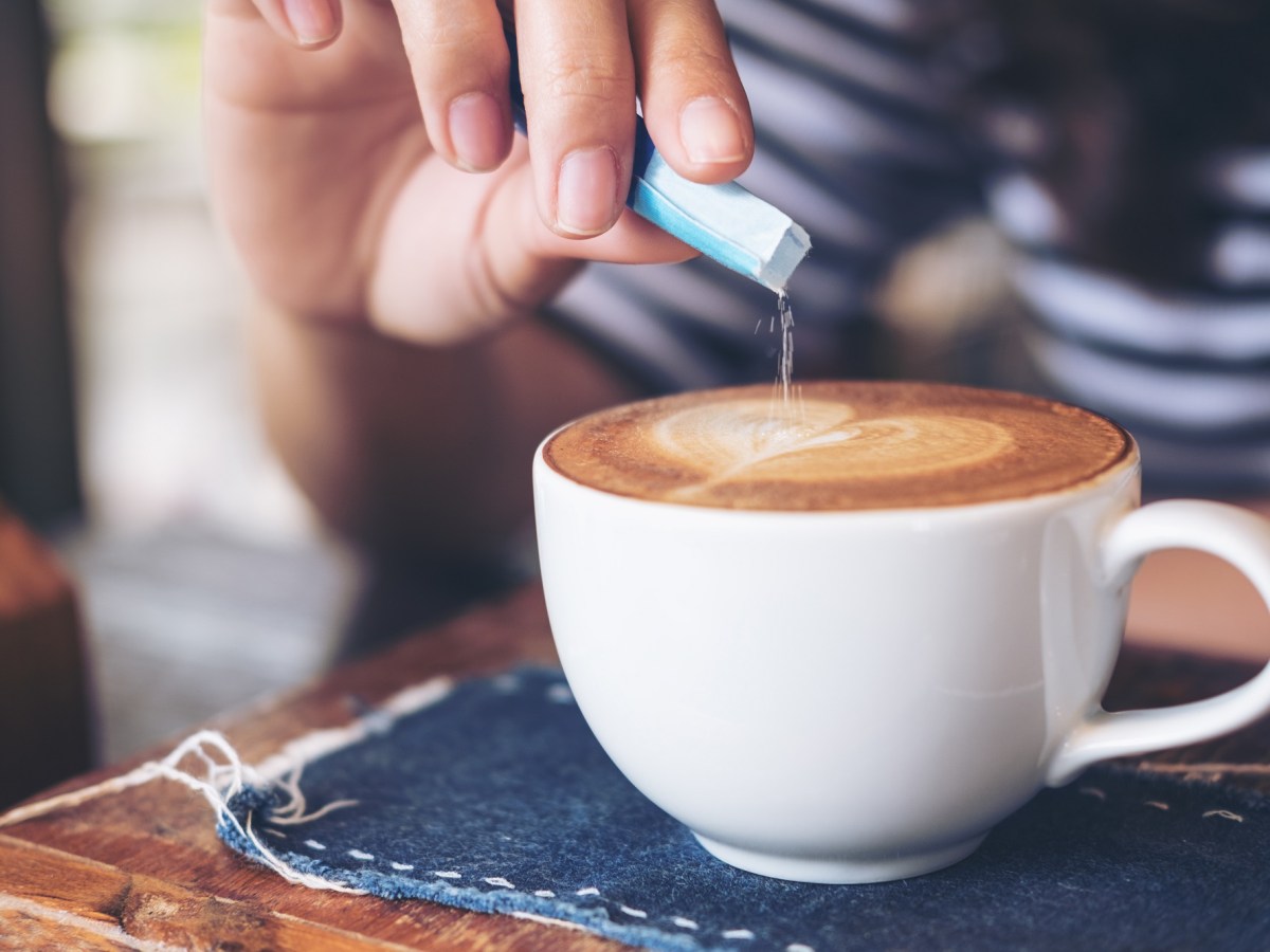 Salz im Kaffee: Eine Frau streut etwas Salz in eine Tasse Kaffee.