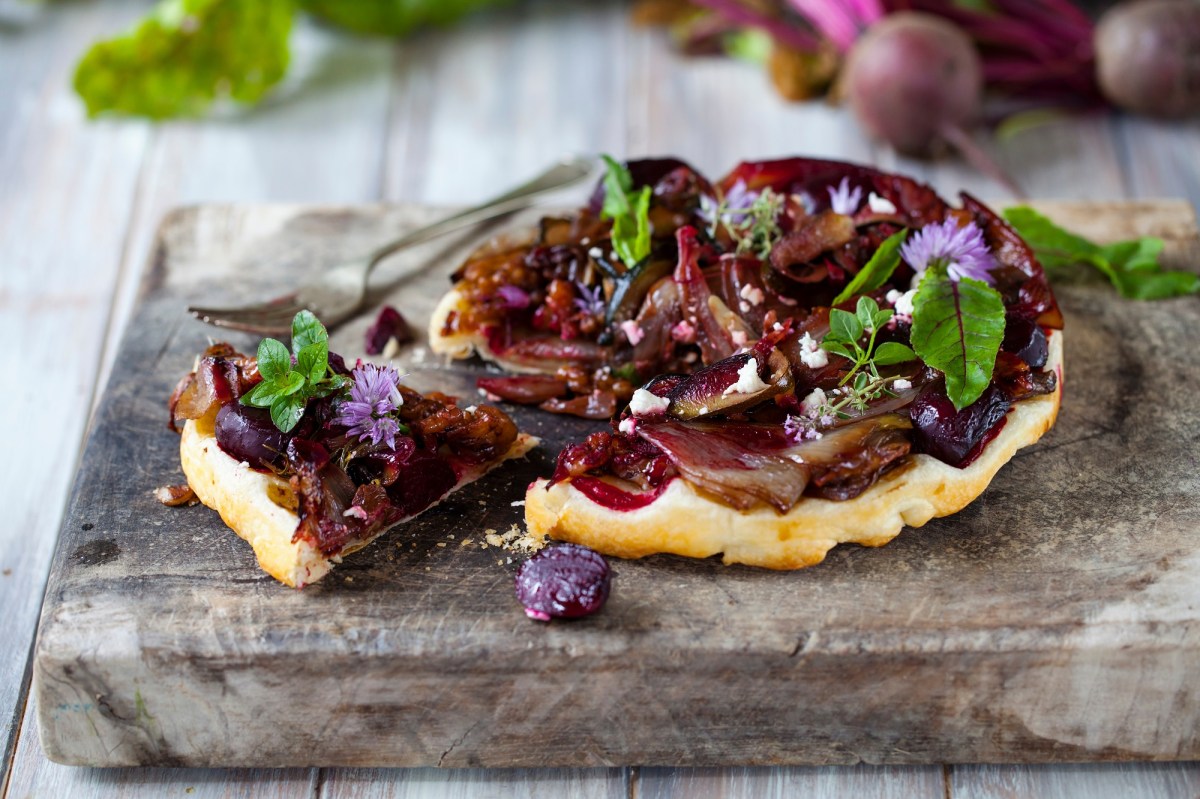 Die Schalotten-Tarte-Tatin, dekoriert mit Salat und essbaren Blumen.