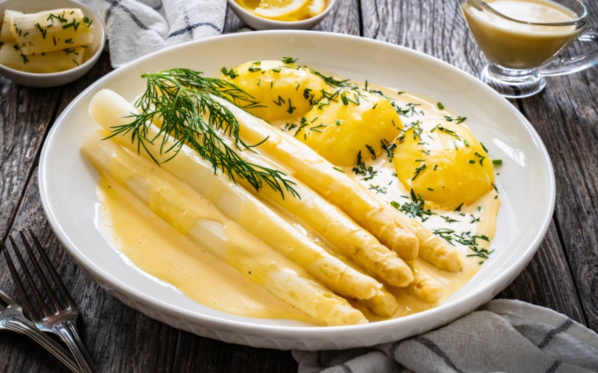 Wie viel Spargel pro Person: eine Portion Spargel mit Sauce hollandaise und Kartoffeln auf einem Teller.