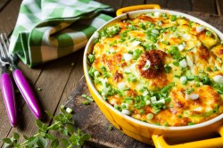 Gelbe Auflaufform mit einem Kartoffel-Zucchini-Auflauf.