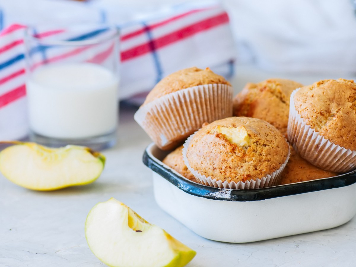 Kleine Schale mit Apfel-Muffins ohne Zucker und Apfelstücken daneben