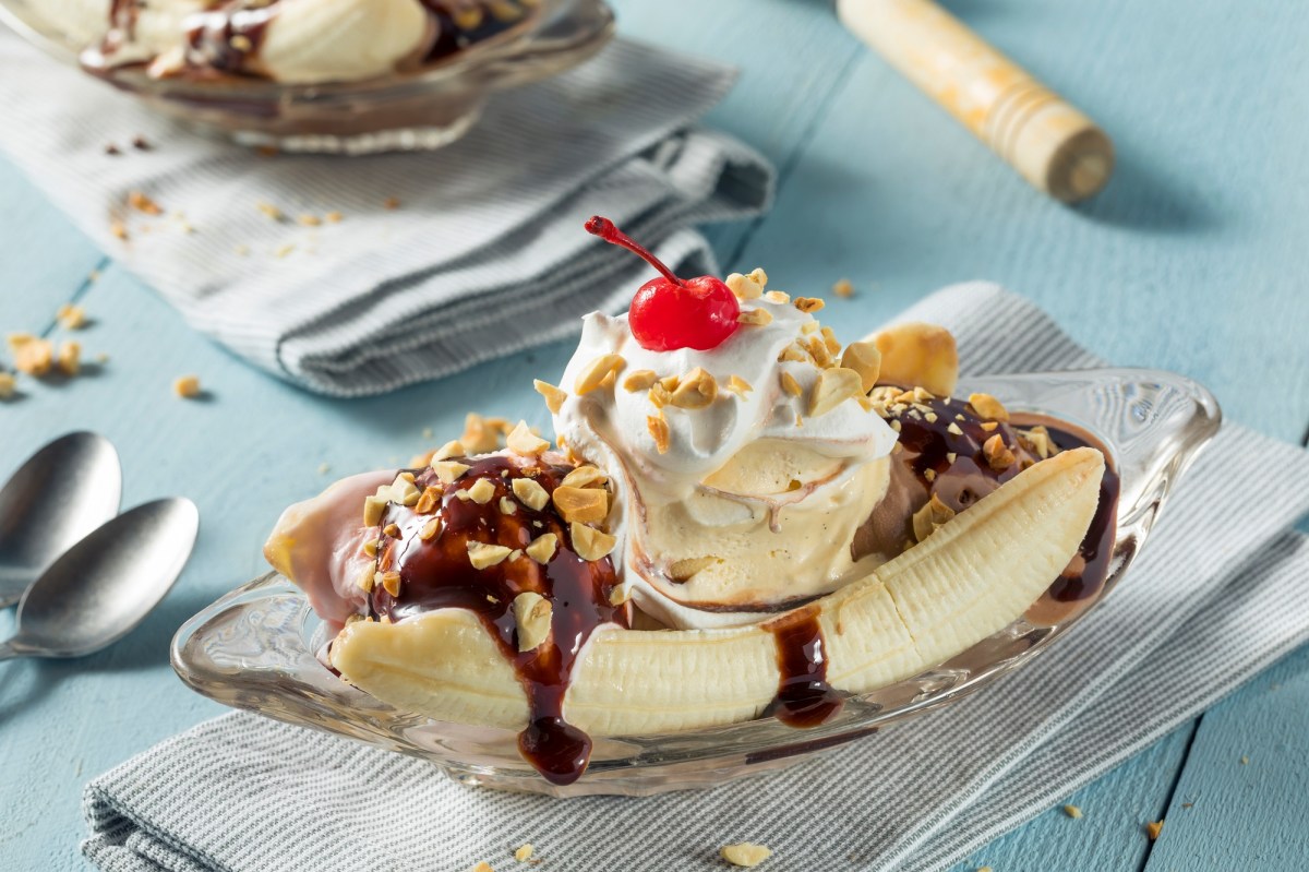 Banana Split auf einem Glasteller auf einer blauen Tischdecke