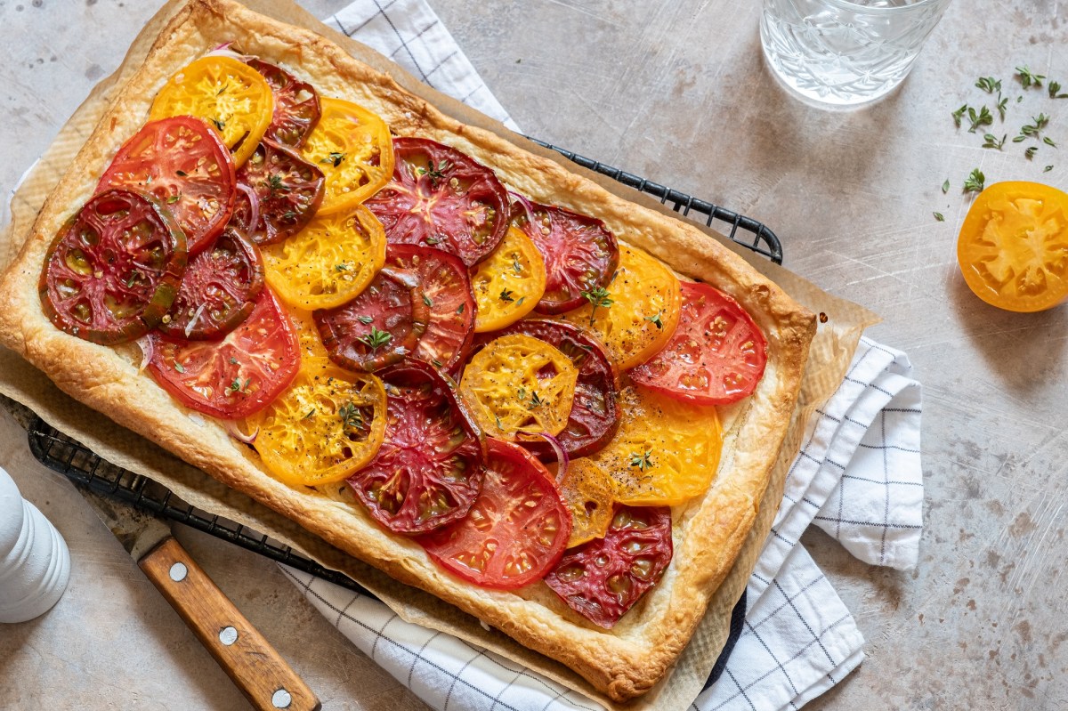 Blätterteig-Tarte mit Tomaten auf einem Kuchengitter, das auf einem Geschirrtuch liegt.