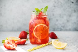 Glas mit Erdbeereistee und Erdbeeren daneben