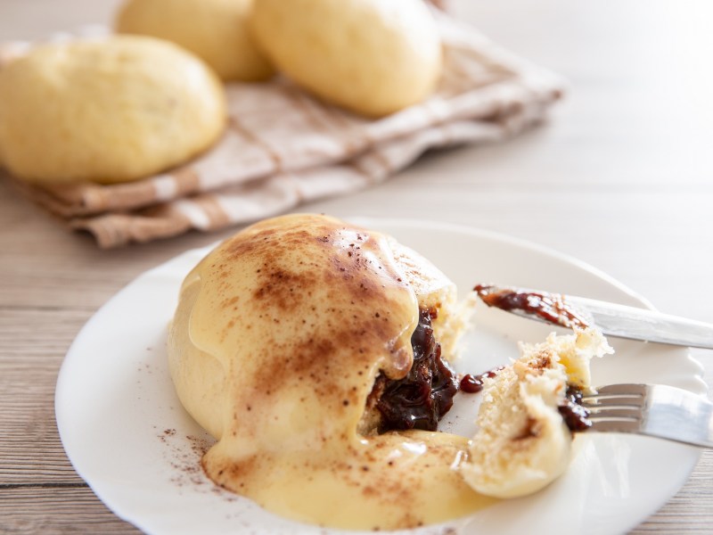 Gefüllte Dampfnudeln mit Vanillesoße und Pflaumenmusfüllung.