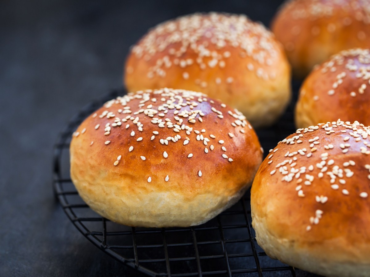 mehrere JoghurtbrÃ¶tchen auf einem Gitter, mit Sesam bestreut.