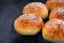 mehrere Joghurtbrötchen auf einem Gitter, mit Sesam bestreut.