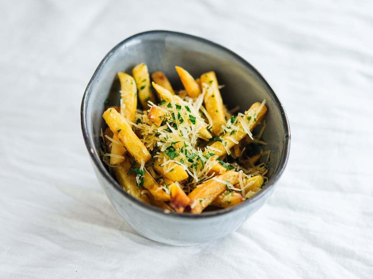 Eine Schale Knoblauch-Parmesan-Fritten mit Petersilie.