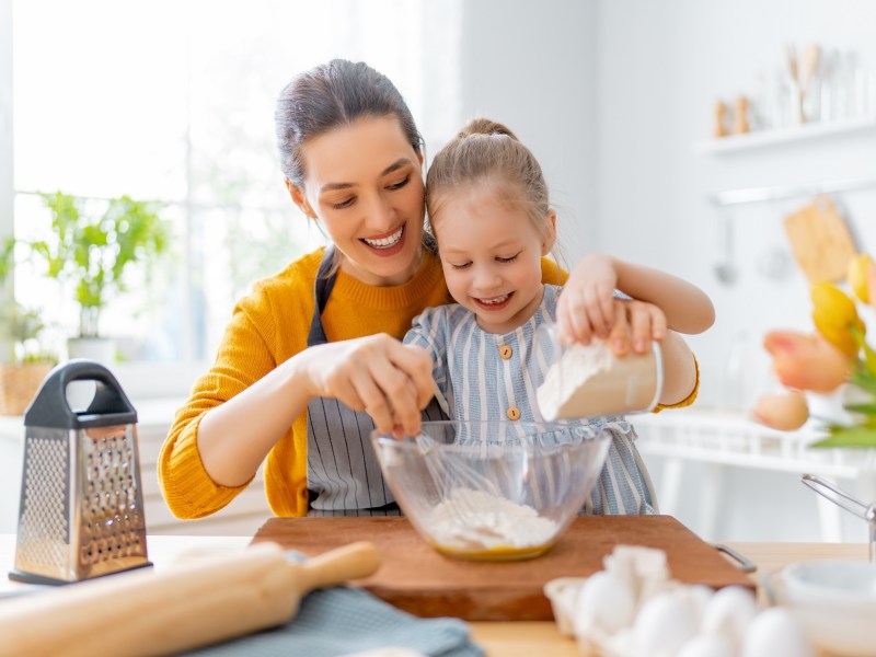 Kochen und Backen mit Kindern: Eine Mutter backt mit ihrer Tochter einen Kuchen.