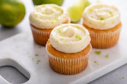 3 Kokos-Limetten-Cupcakes auf einem Brett.