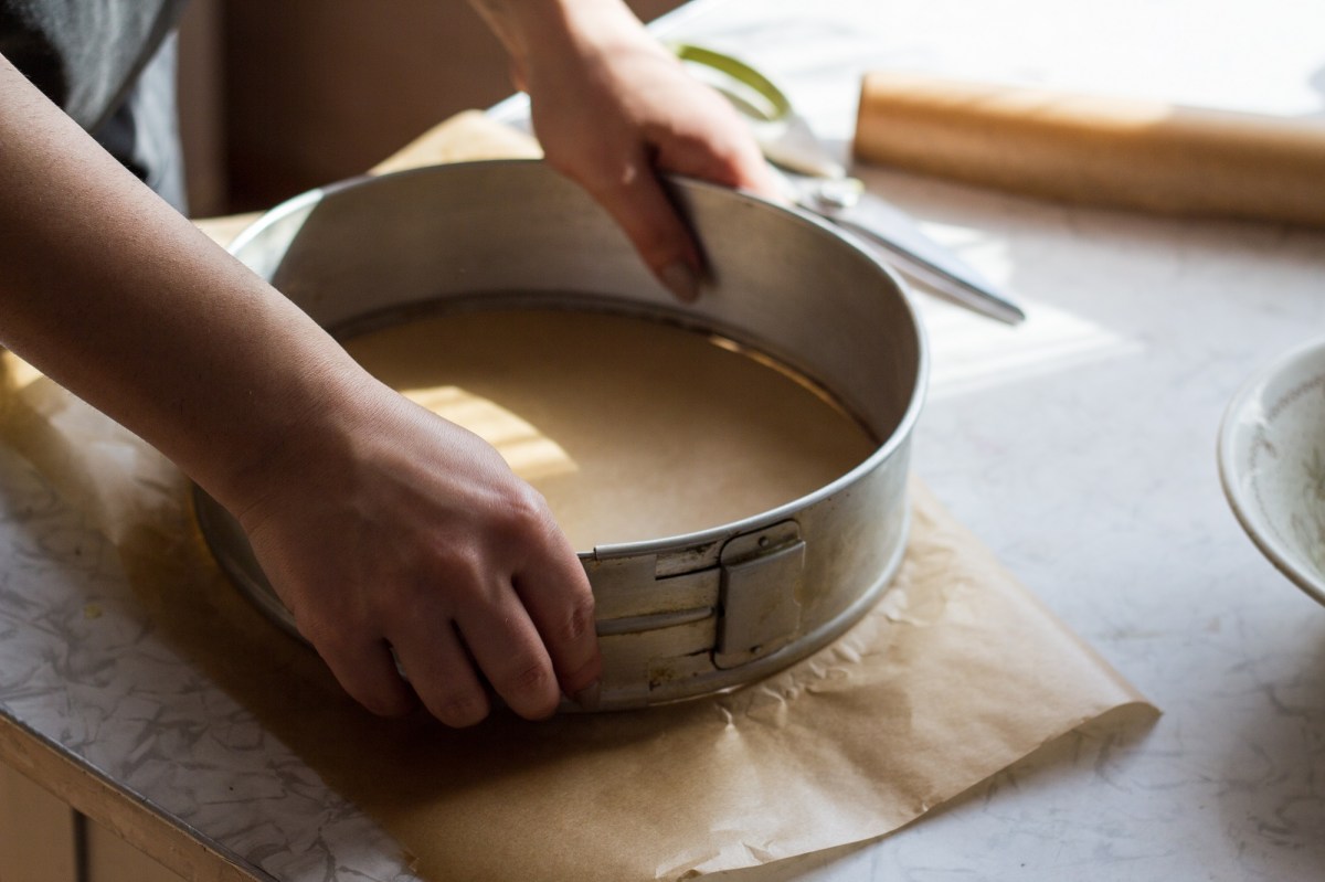 Eine Frau ist dabei, eine Kuchenform mit Backpapier auszulegen.