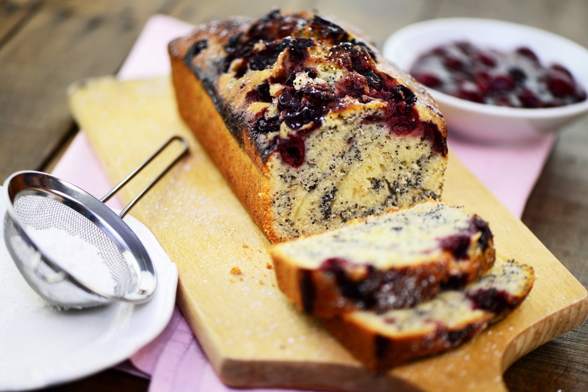 Angeschnittener Mohnkuchen mit Kirschen auf einem Holzbrett