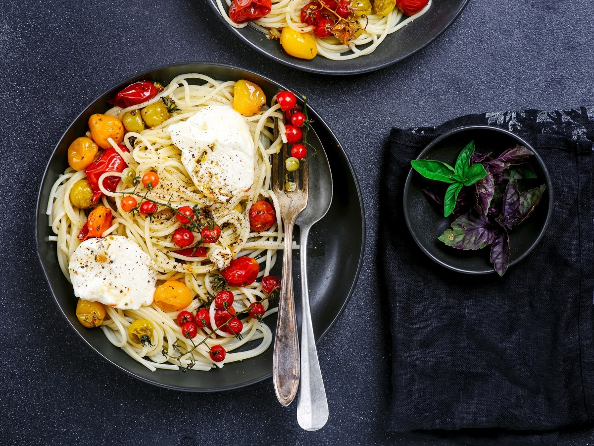 Ein Teller mit Spaghetti mit Burrata und gegrillten Tomaten.