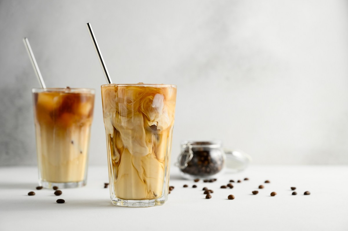 Eiskaffee selber machen: zwei Eiskaffees in Gläsern mit Trinkhalm aus Metall, daneben Kaffeebohnen.