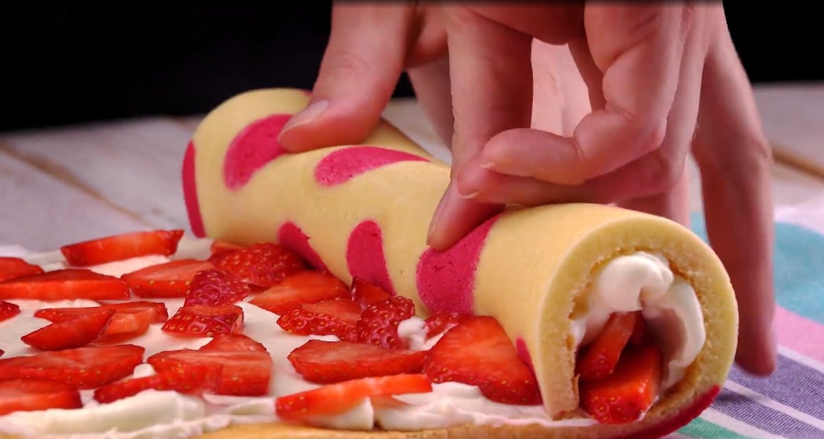 Eine Erdbeer-Käsekuchen-Rolle wird aufgerollt