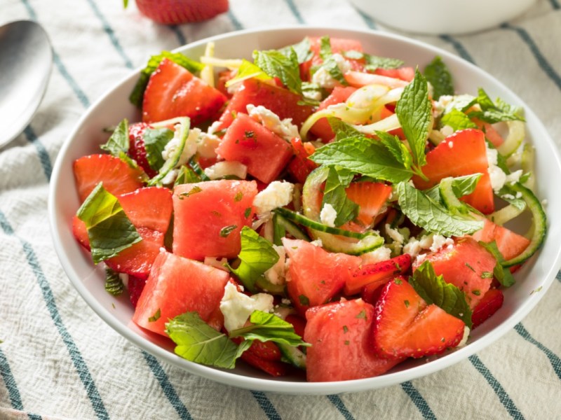 Ein Erdbeer-Melonen-Salat mit Feta in einer flachen Schale.