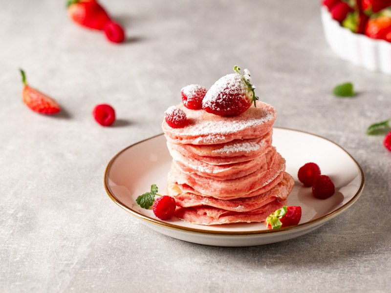 Teller mit pinken Pancakes, Erdbeeren und Himbeeren