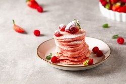 Teller mit pinken Pancakes, Erdbeeren und Himbeeren