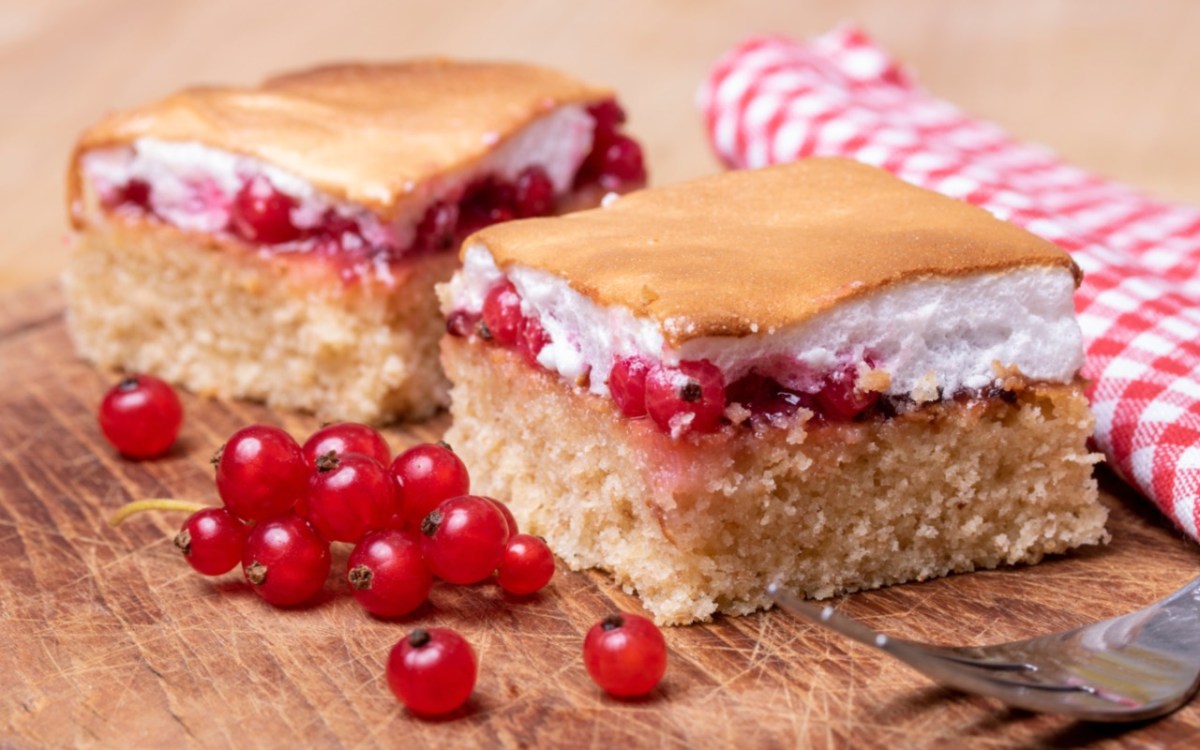 Zwei Stücke Ribiselkuchen. Daneben frische Johannisbeeren.