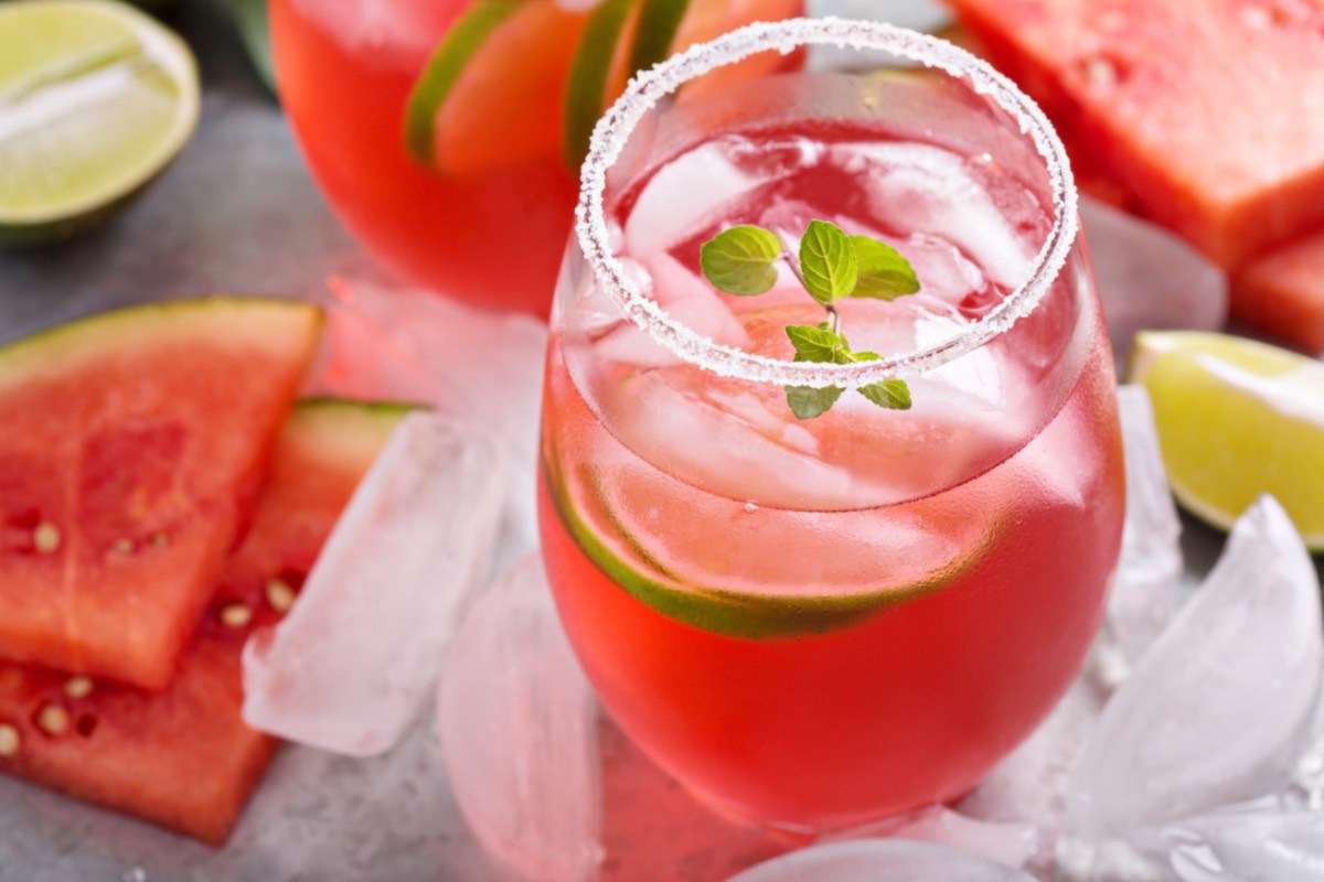 Ein Glas Watermelon Man. Drumherum liegen Limetten, EiswÃ¼rfel und frische Wassermelone.