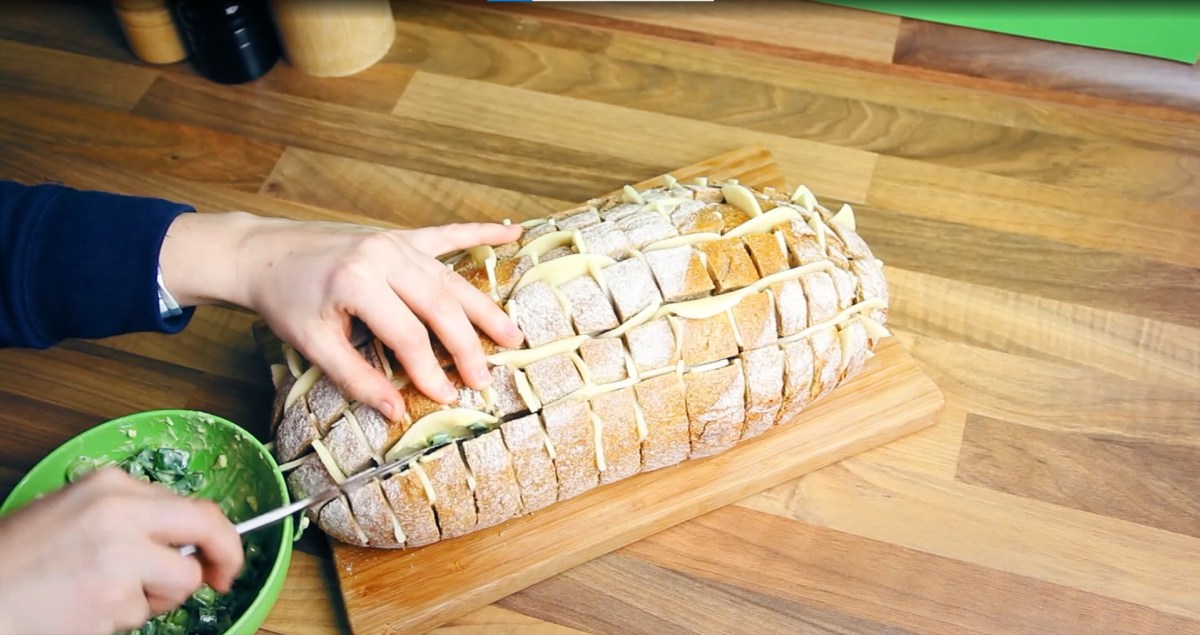 Ein Zupfbrot mit Käse und Knoblauchbutter auf einem Holzbrett.