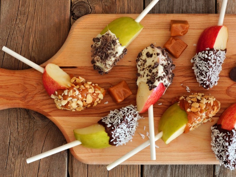 Apfel-Lollies am Stiel mit Schokolade und Toppings.