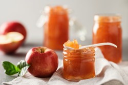 Ein Schälchen mit Apfel-Salzkaramell-Marmelade. Dahinter liegen frische Äpfel.