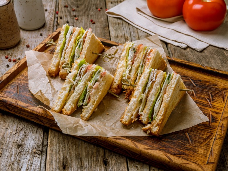 Mehrere Stücke Club Sandwich auf einem Holzbrett.