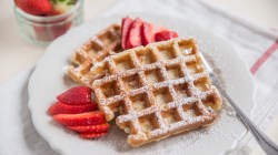 Dinkel-Waffeln mit Erdbeeren auf weißem Teller.