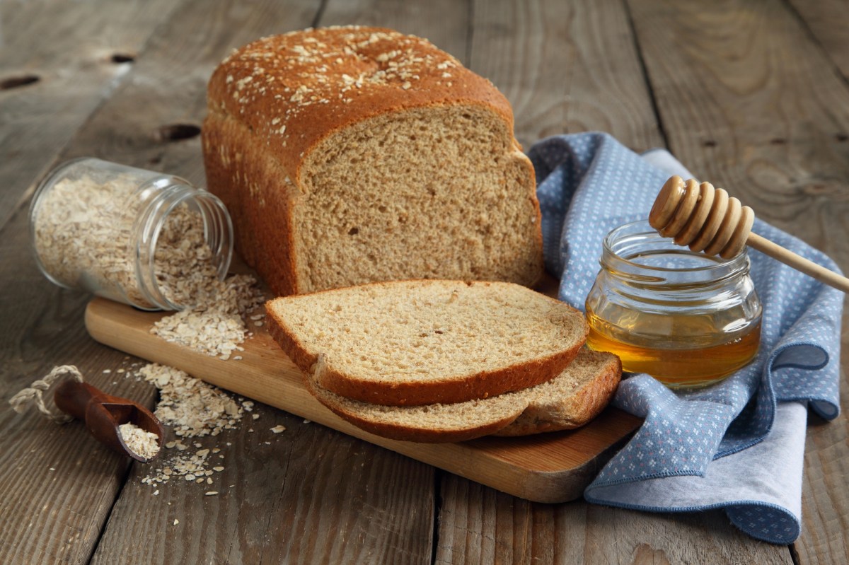 Ein angeschnittenes Honigbrot auf einem Holzbrett.