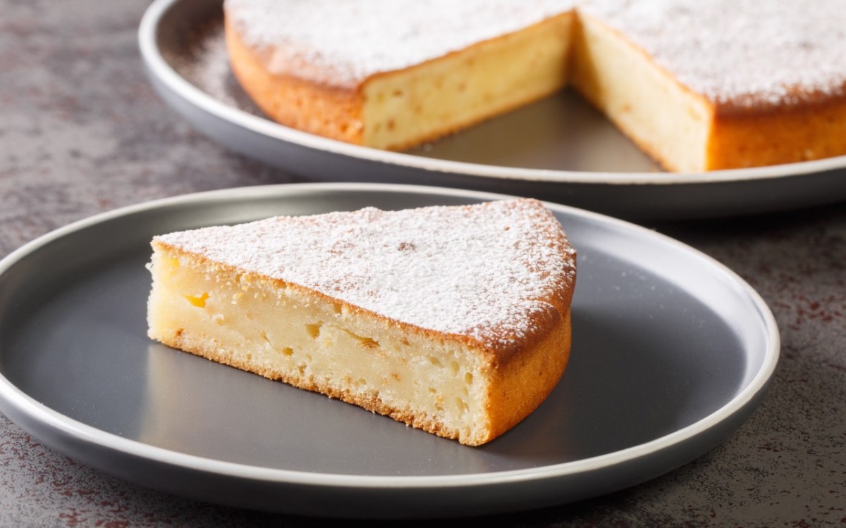 Ein StÃ¼ck Joghurtkuchen mit 3 Zutaten auf einem Teller. Im Hintergrund der restliche Kuchen.