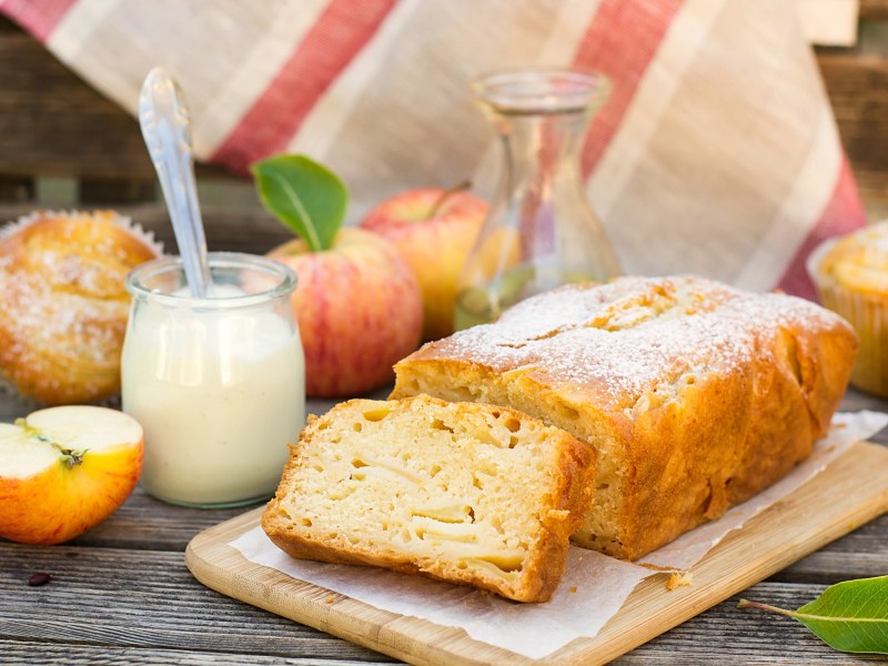 Ein Joghurtkuchen mit Apfel auf einem Holzbrett.