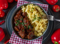 Ein Teller Nudeln mit Gulasch.