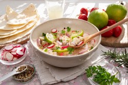 Peruanische Ceviche in einer hellen Schale. Drum herum liegen Limetten, Chilis und Maisfladen.