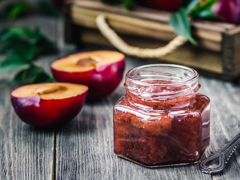 Pflaumen-Birnen-Chutney in kleinem Glas auf dunklem Tisch.