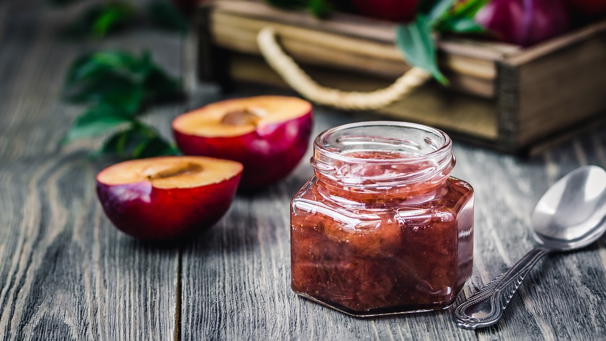 Pflaumen-Birnen-Chutney in kleinem Glas auf dunklem Tisch.