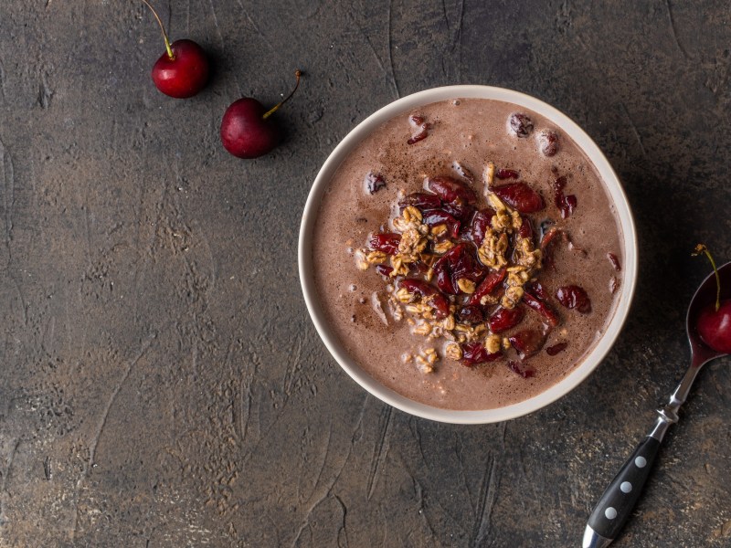 Eine Schüssel Schwarzwälder-Kirsch-Porridge mit Kirschen getoppt, Draufsicht.