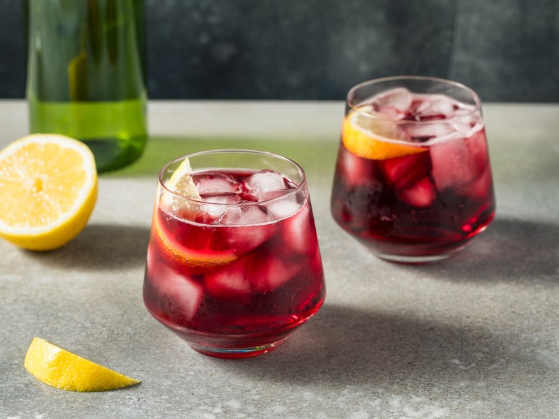 Zwei Gläser Tinto de Verano. Daneben liegt eine halbe Zitrone.