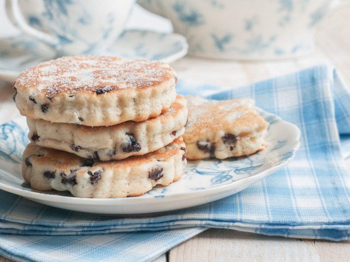 Welsh Cakes Ã¼bereinandergestapelt auf einem Teller. Dieser steht auf einer blau-weiÃŸ-karierten Serviette.