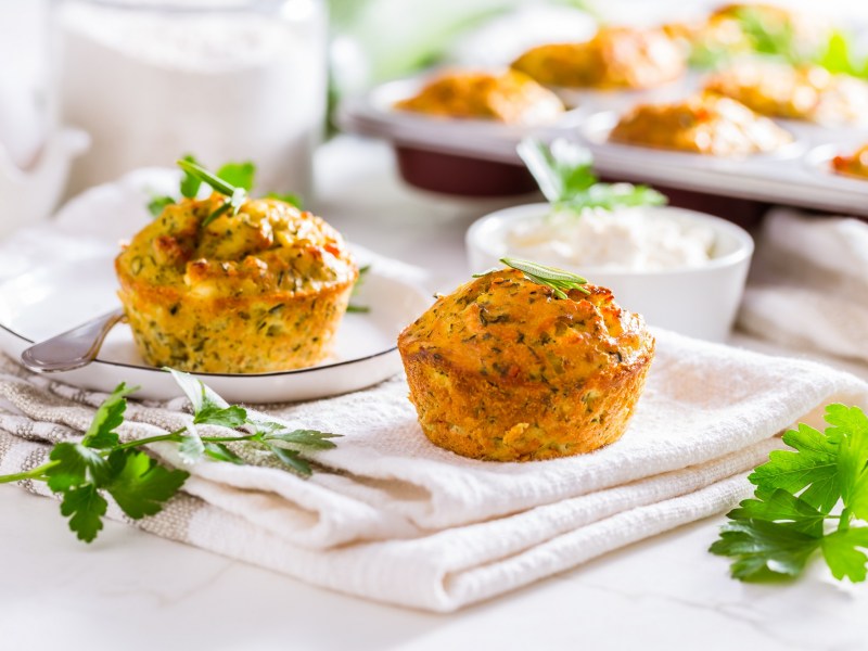 Zwei Zucchini-Feta-Muffins auf einem Tuch.