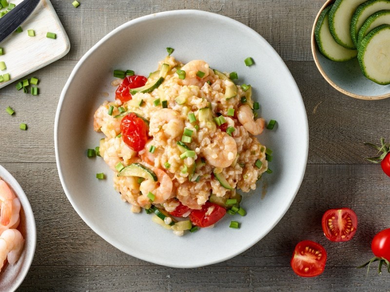 Zucchini-risotto-mit Garnelen auf einem weißen Teller.